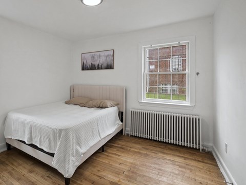 A bedroom with a bed, a window, and a radiator.