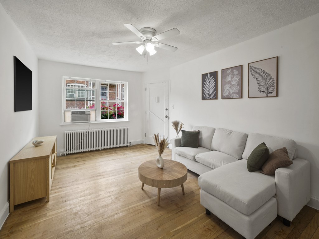 A living room with a white couch, wooden coffee table, and a ceiling fan.