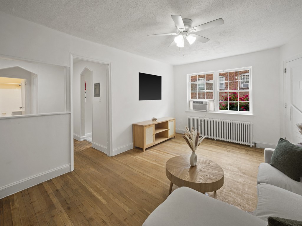 A living room with a wooden floor and a ceiling fan.
