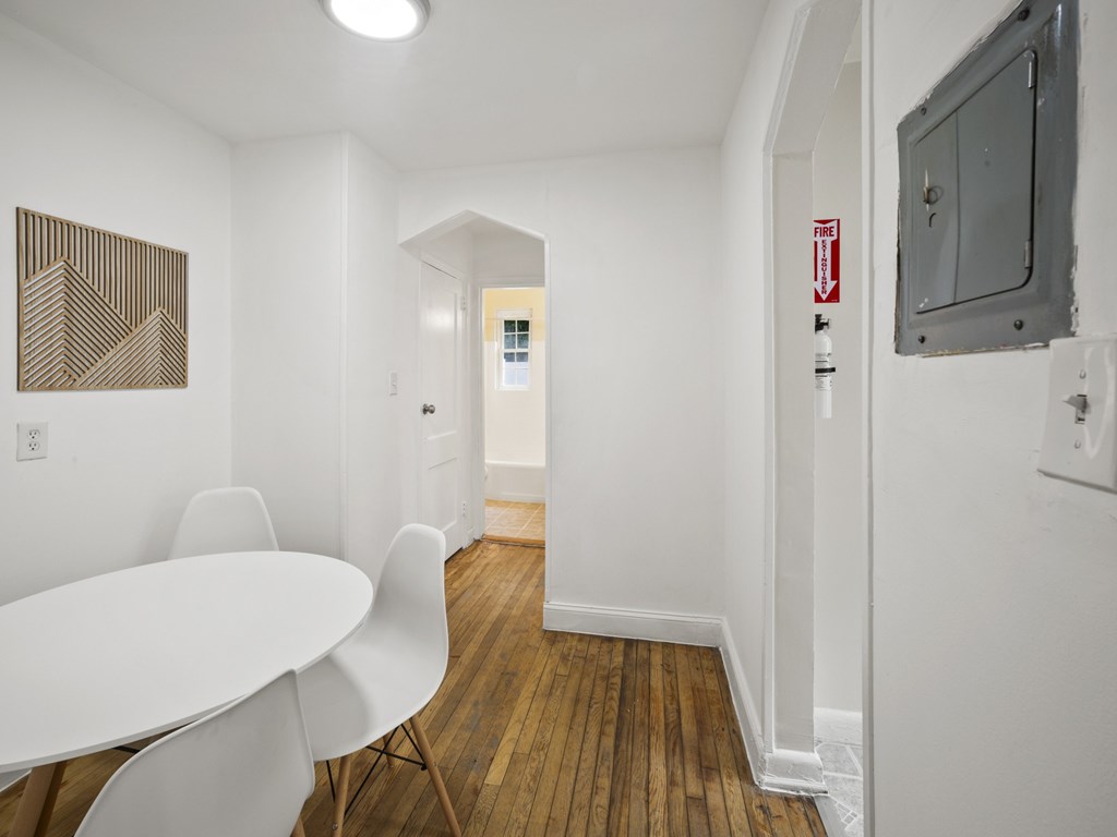 A white table with chairs in a room with wood floors.