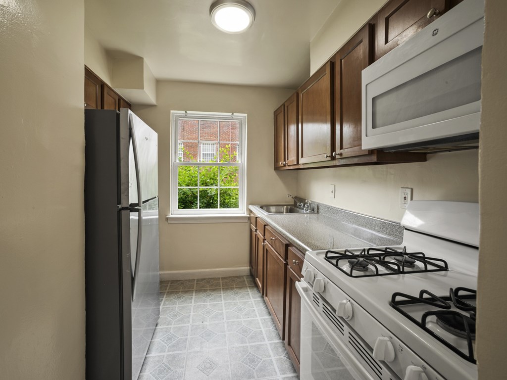 A kitchen with a black refrigerator, white stove, and wooden cabinets.