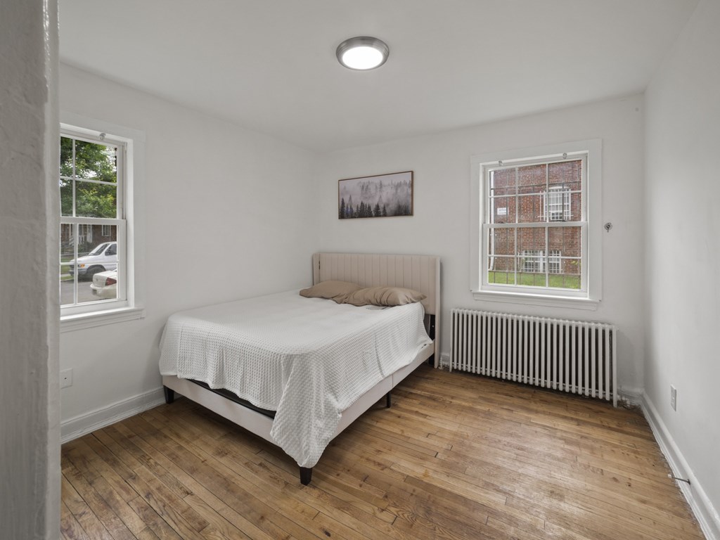 A bedroom with a bed, a window, and a picture on the wall.