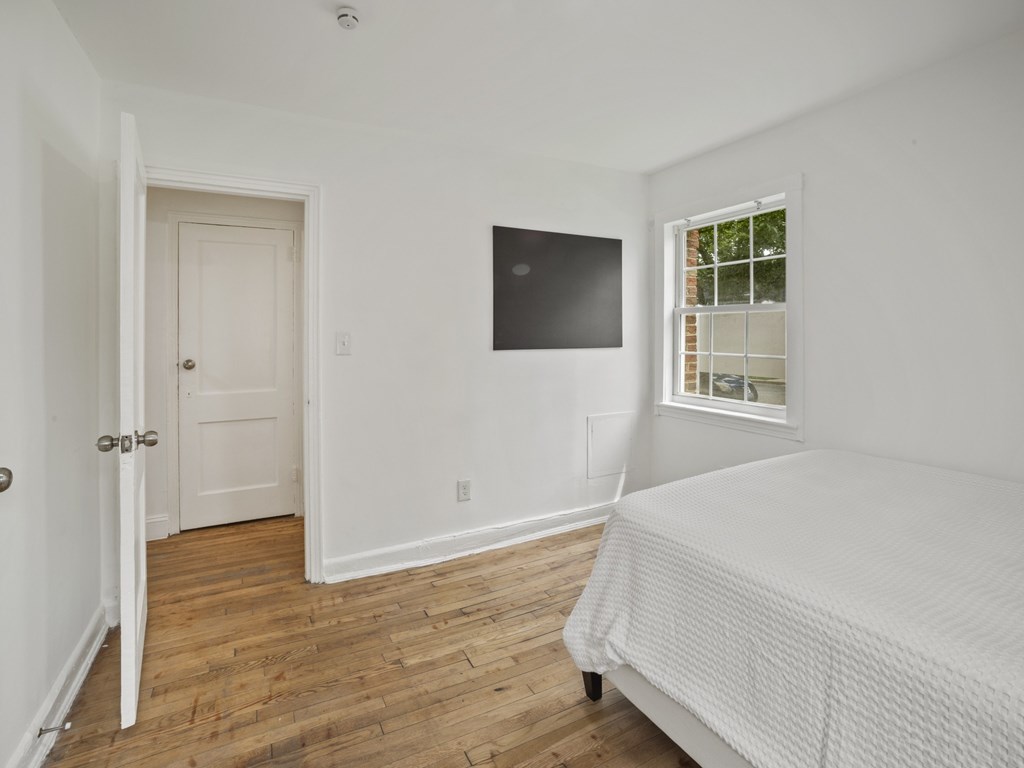 A bedroom with a bed, a door, and a window.