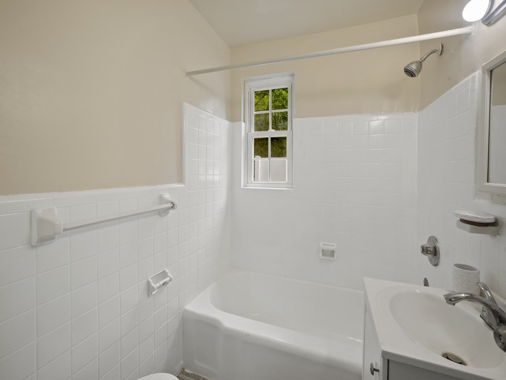 A white bathroom with a tub, sink, and toilet.
