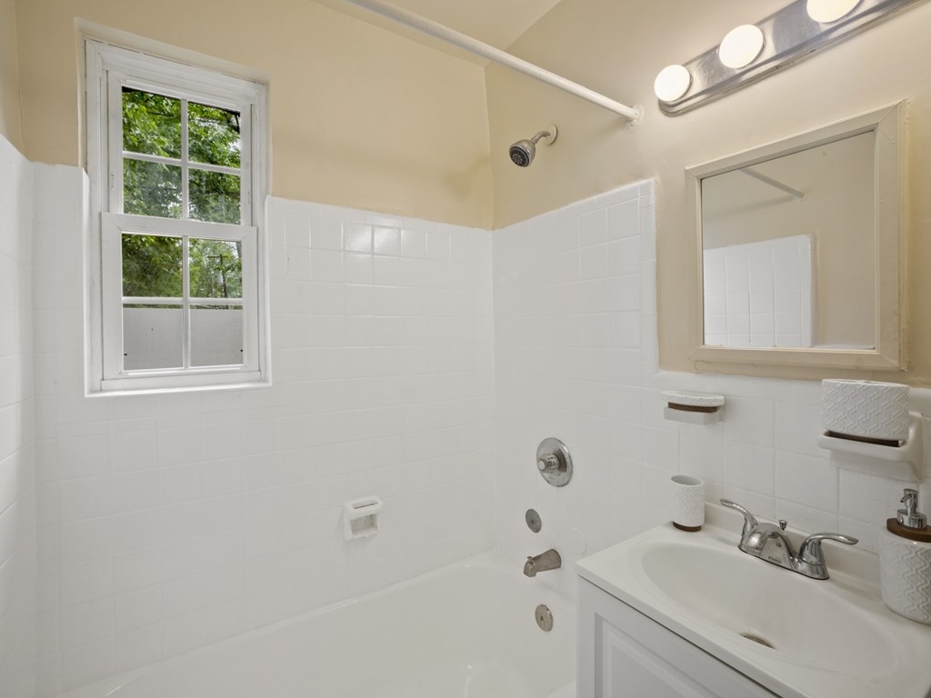 A white bathroom with a window and a sink.