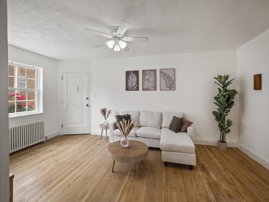 A living room with a white couch, a coffee table, and a ceiling fan.