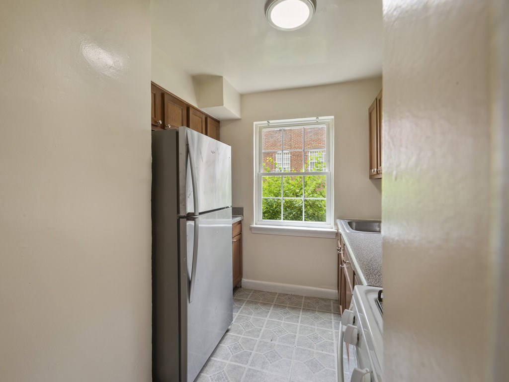 A kitchen with a refrigerator, sink, and window.