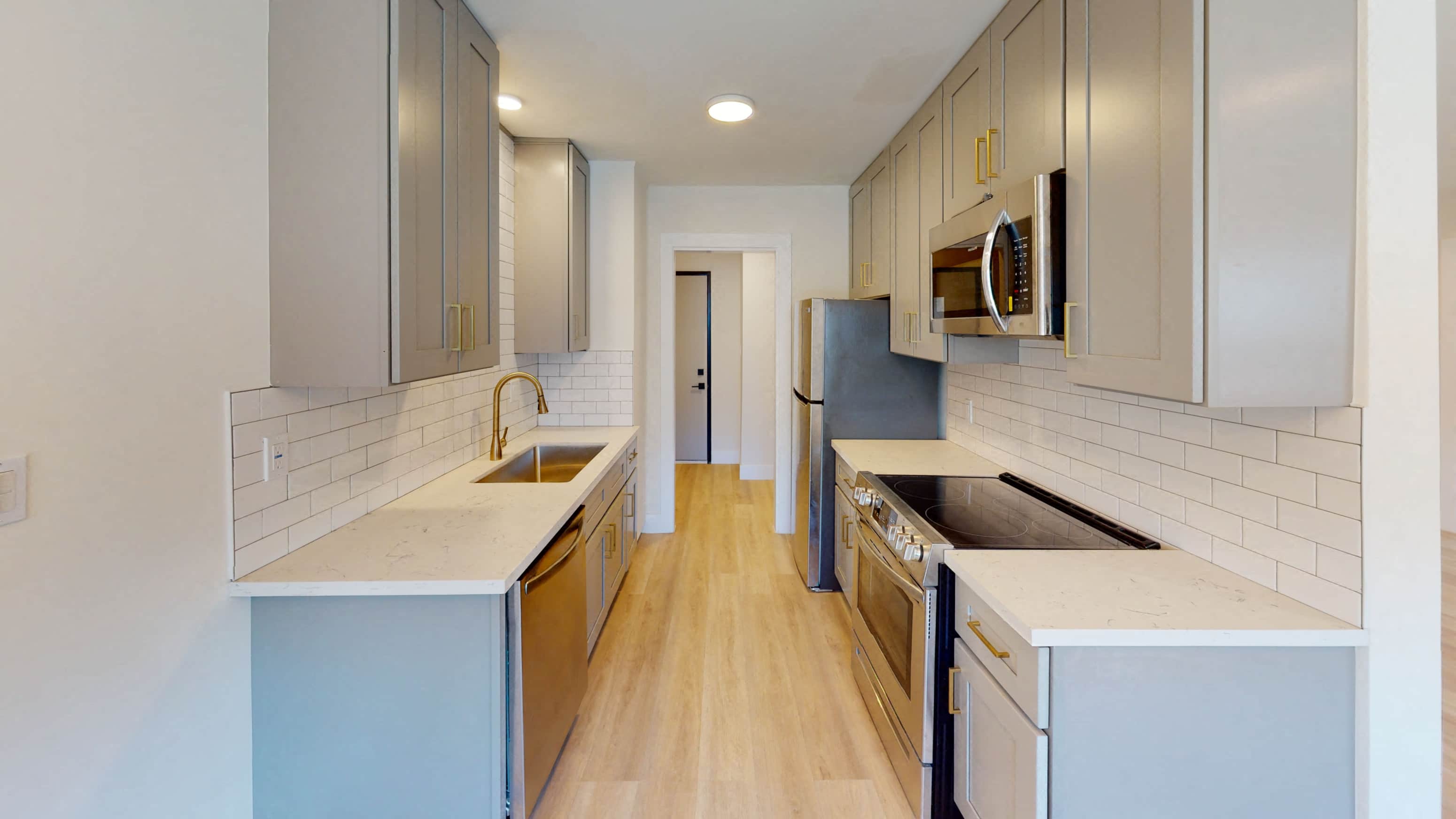 A kitchen with a white counter top and wooden floors.