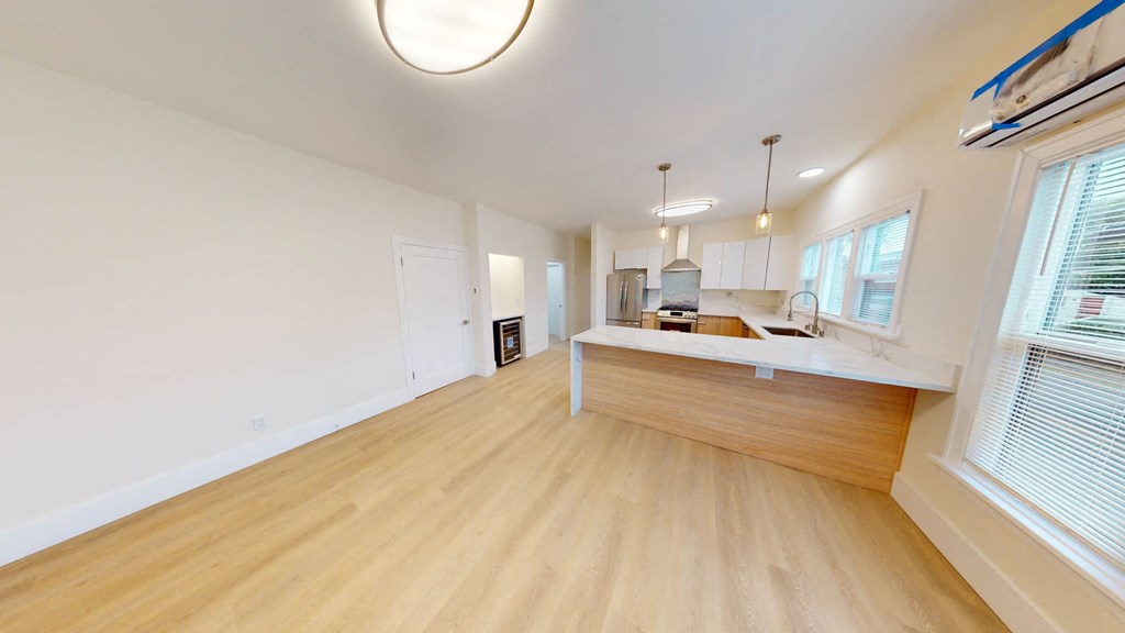 a living room and kitchen with wood floors and white walls