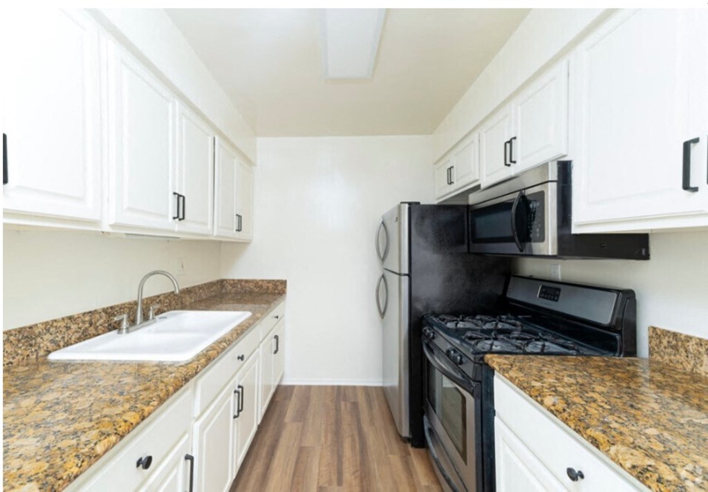 a kitchen with white cabinets and black appliances and granite counter tops