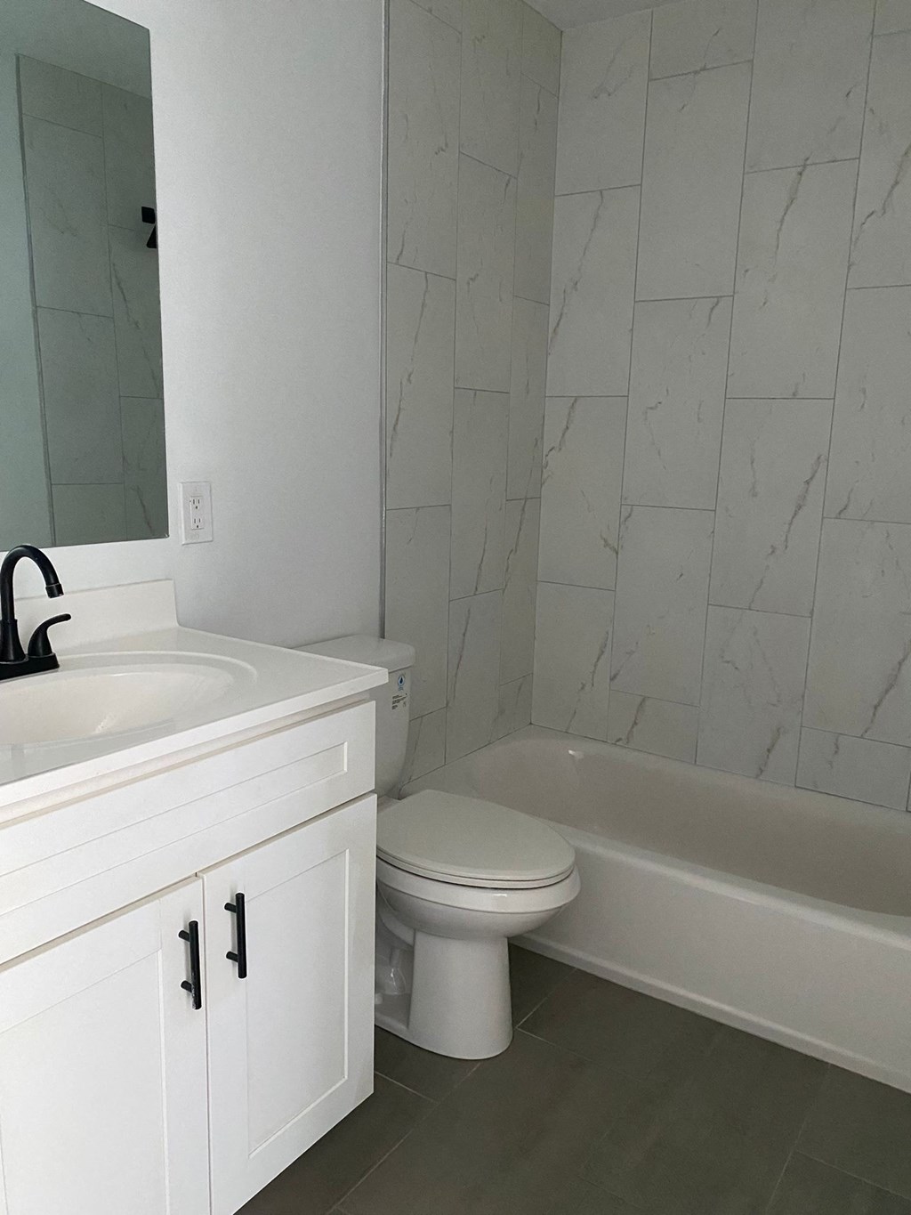 A white bathroom with a marble wall.