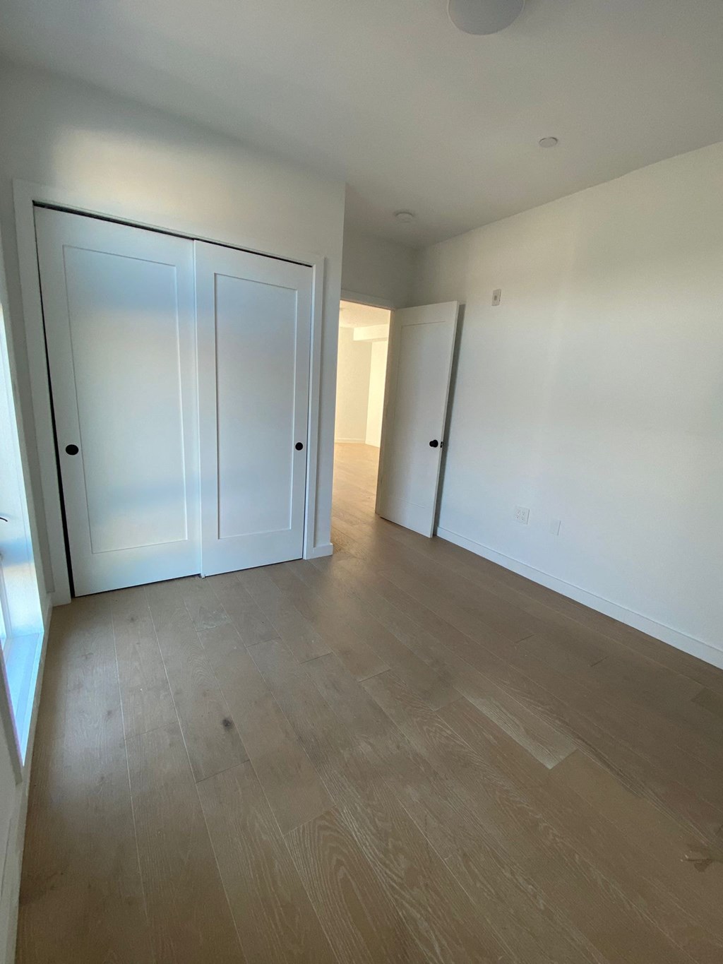 A room with a white door and a wooden floor.