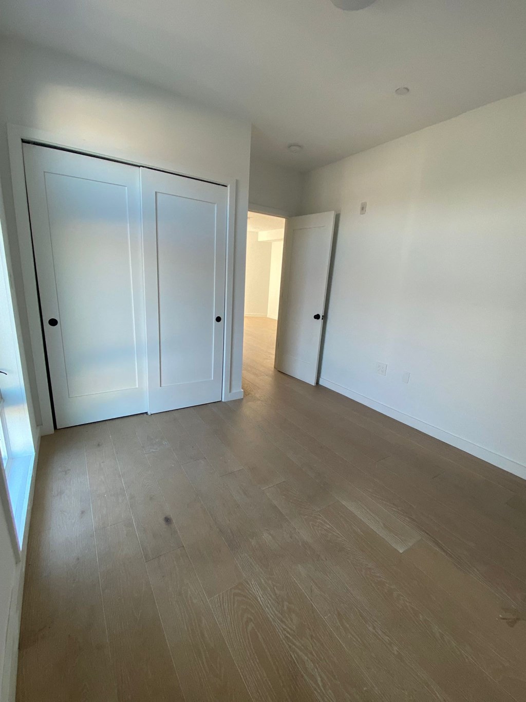 A room with a white door and a wooden floor.