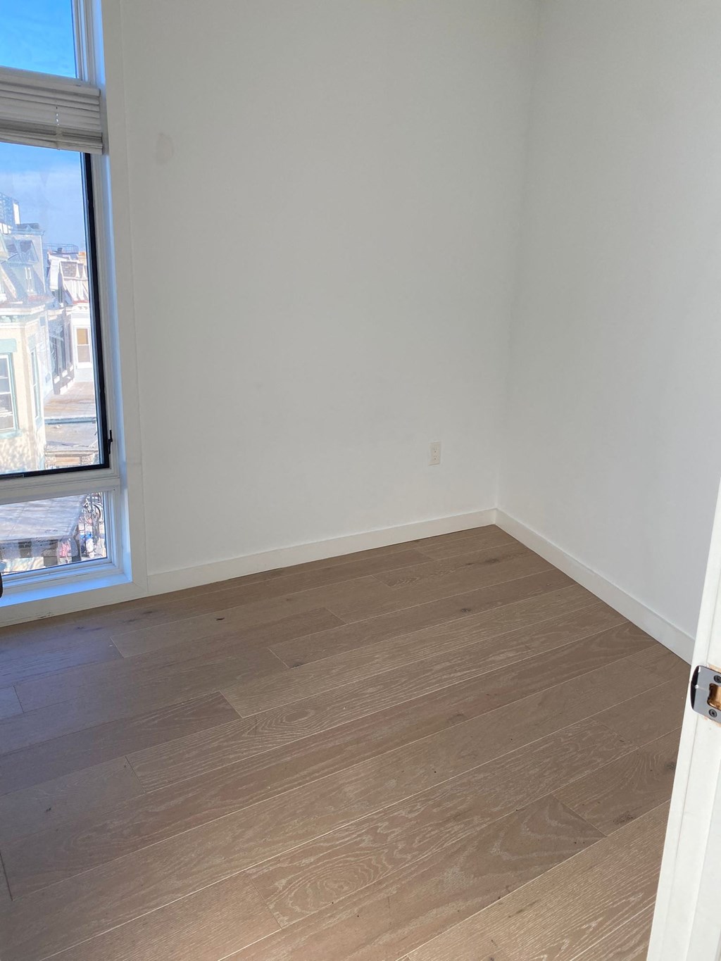 A room with a window and wooden flooring.