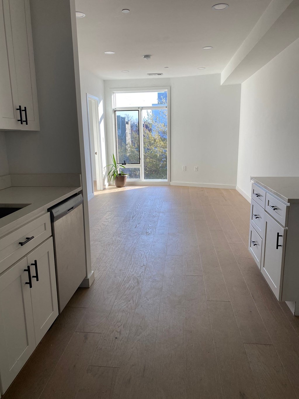 A kitchen with white cabinets and a wooden floor.