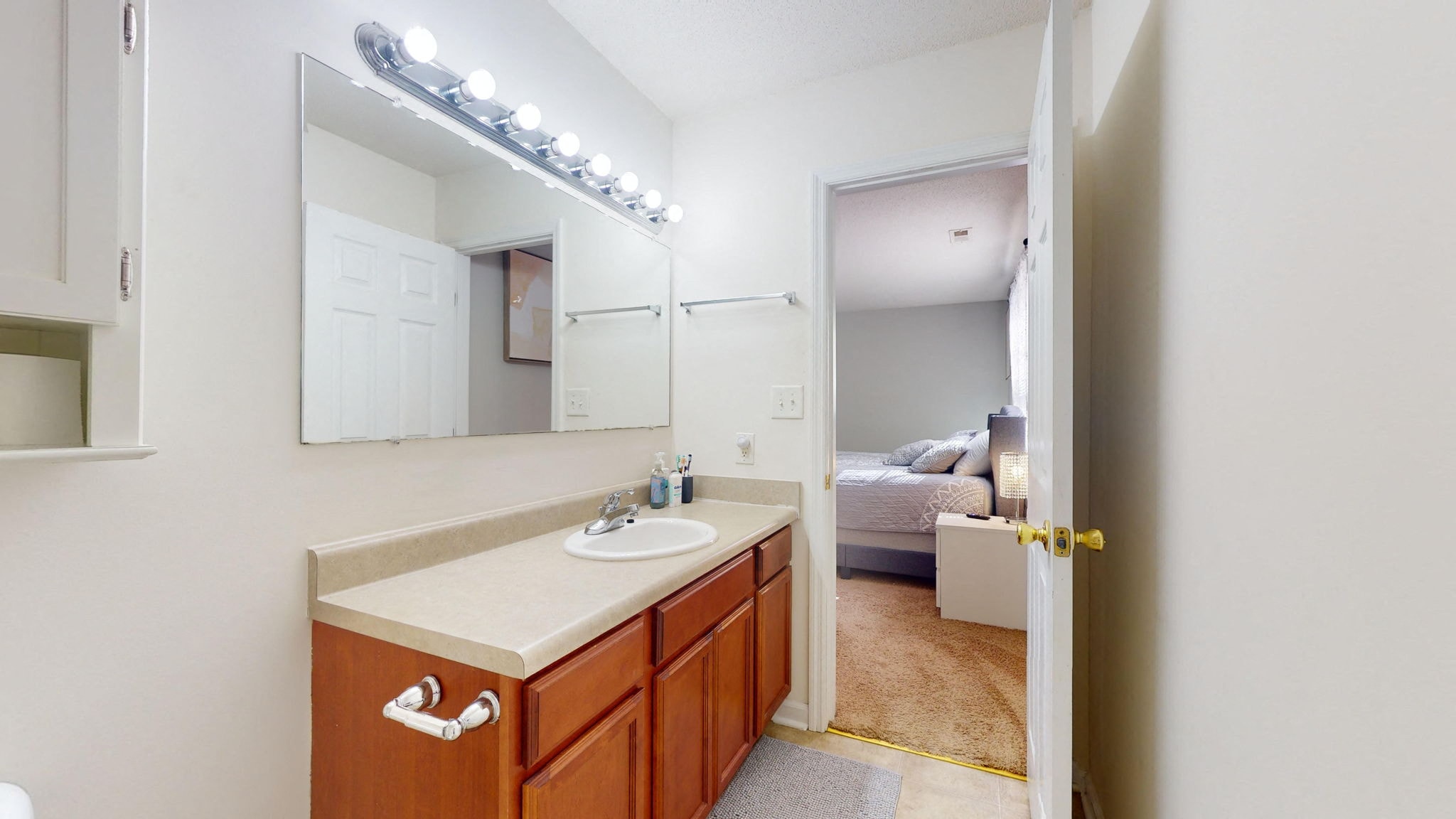 a bathroom with a sink and a mirror and a bedroom