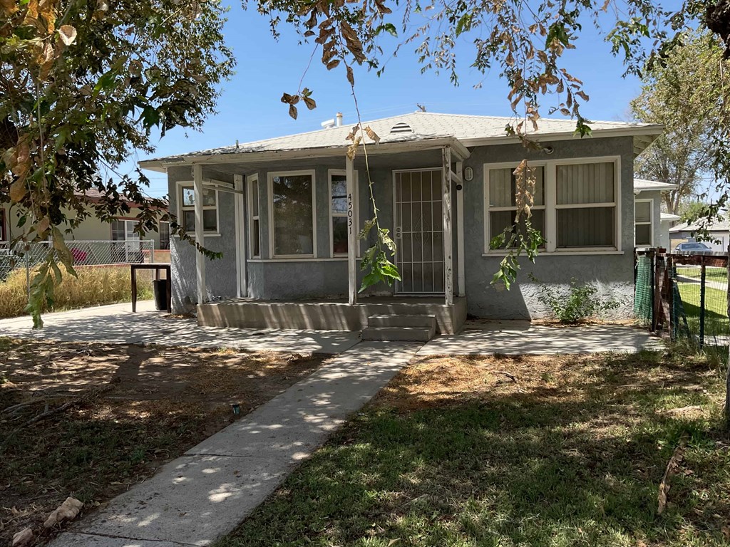 a small gray house with a sidewalk in front of it