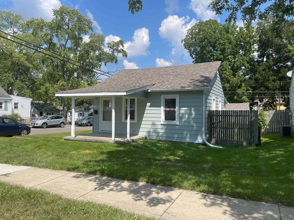a small blue house with a lawn and a sidewalk