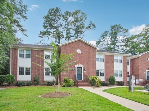 A red brick building with white trim and a green door.