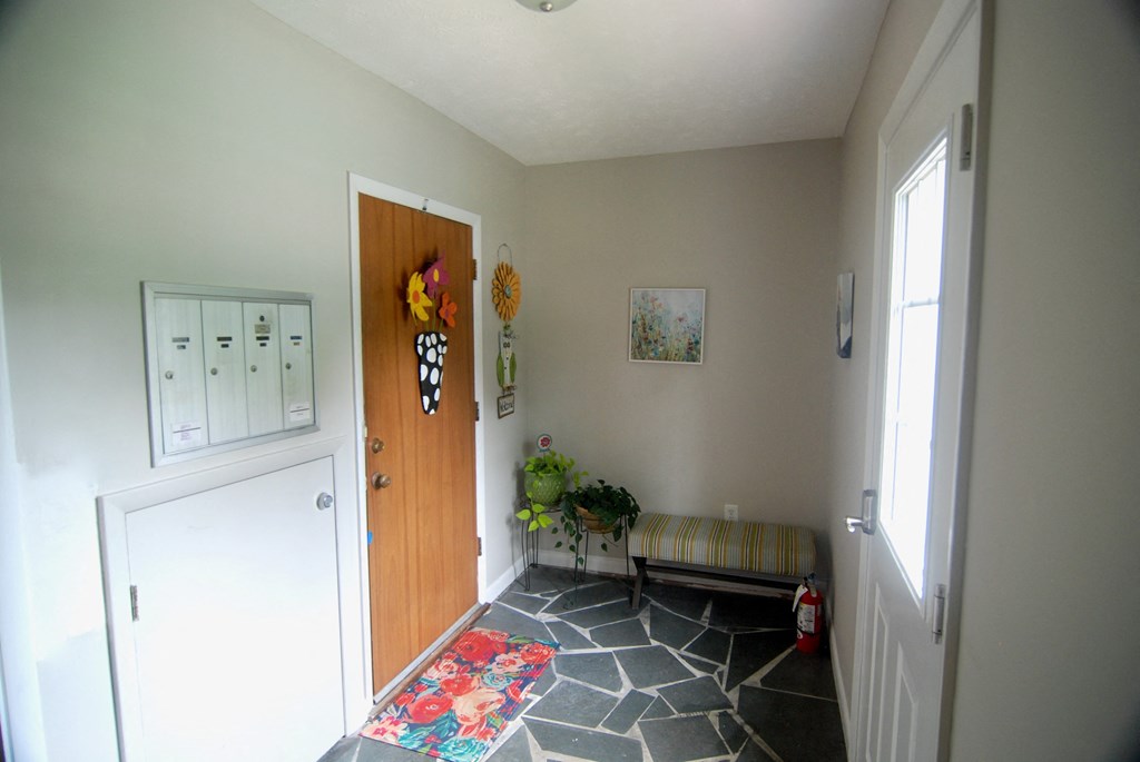 A hallway with a wooden door and a bench.