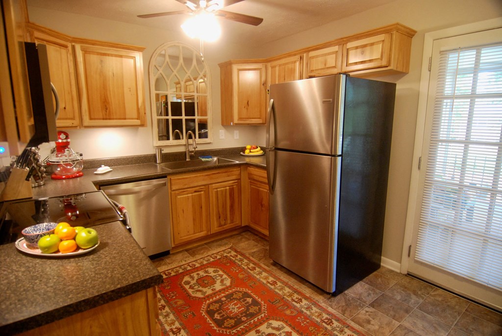 A kitchen with wooden cabinets and a stainless steel refrigerator.