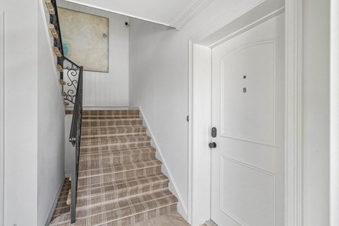 a stairway in a home with white walls and a white door
