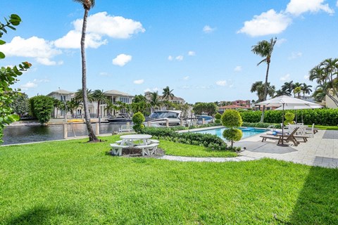 a backyard with a pool and picnic table and palm trees