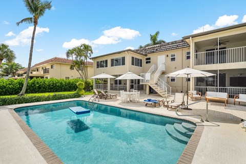 a swimming pool with chairs and umbrellas in front of a house