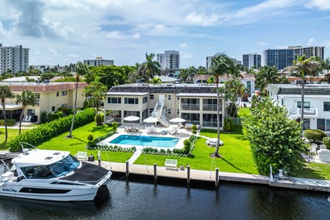 a yacht is docked in front of a house with a swimming pool