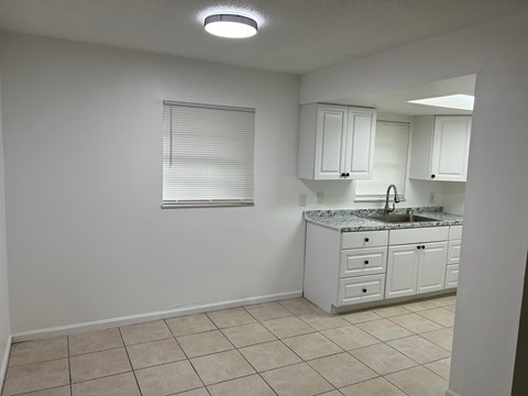 A kitchen with white cabinets and a granite countertop.
