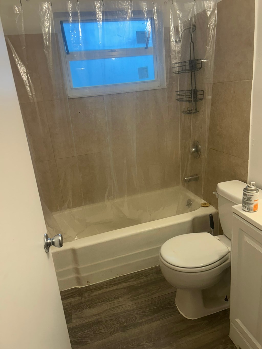 A bathroom with a toilet, tub, and a window.