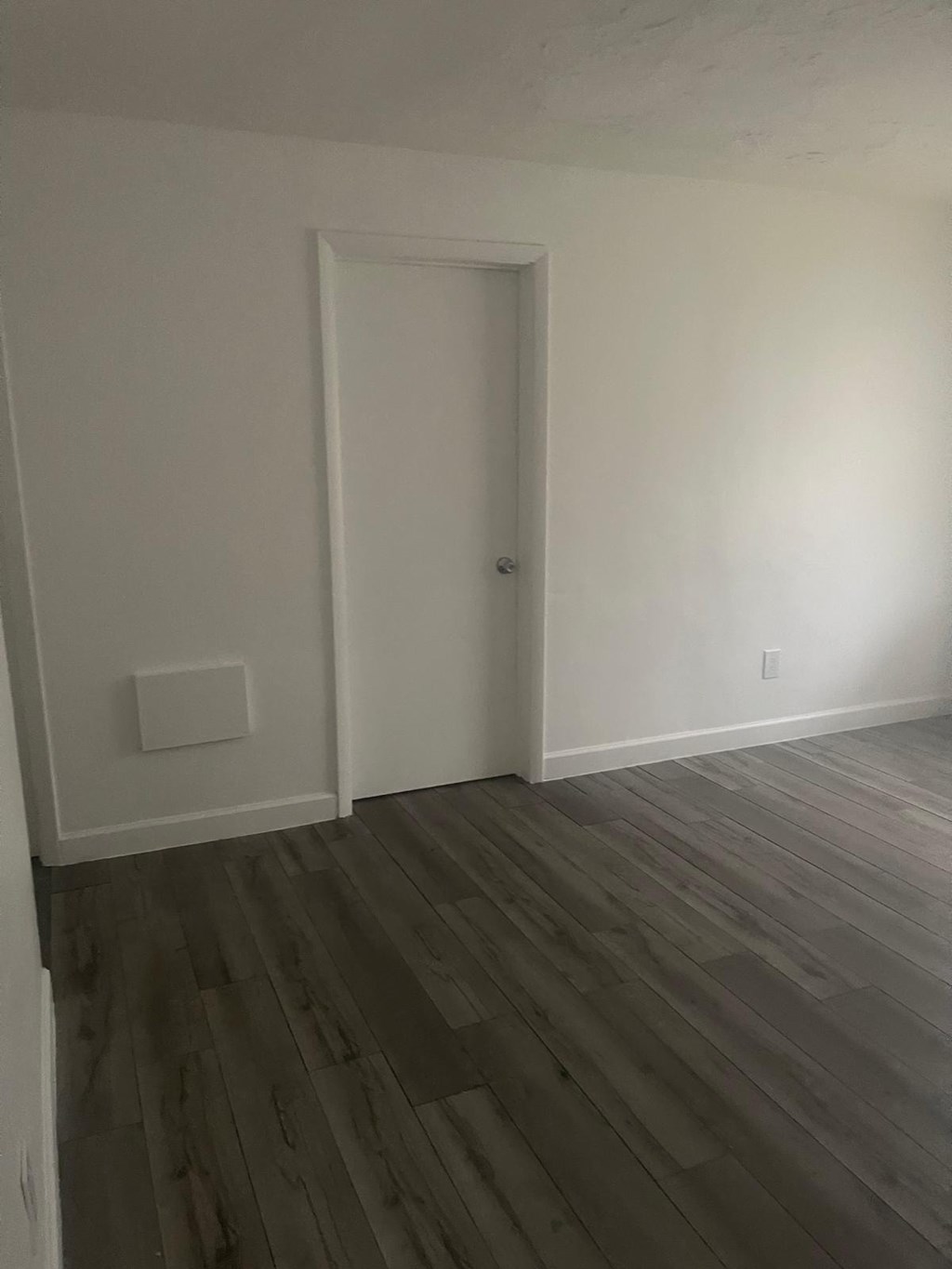 A room with a white door and a wooden floor.