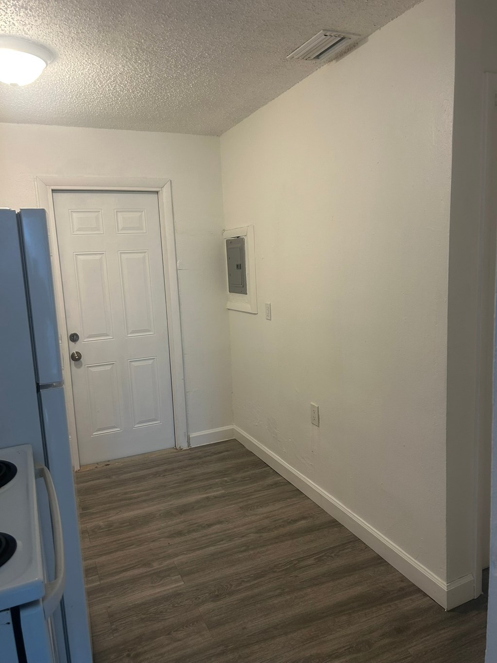 A white door is in a room with a light blue refrigerator.