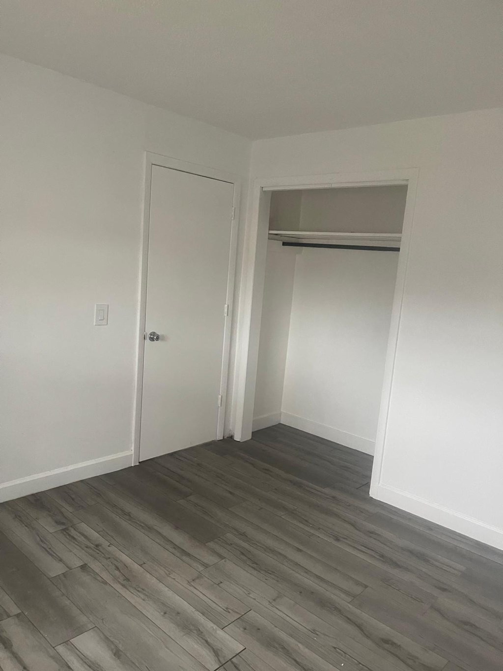 A room with a white door and a grey floor.