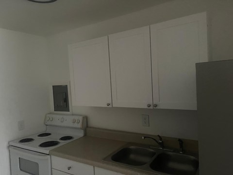 A kitchen with white cabinets and a white stove top oven.