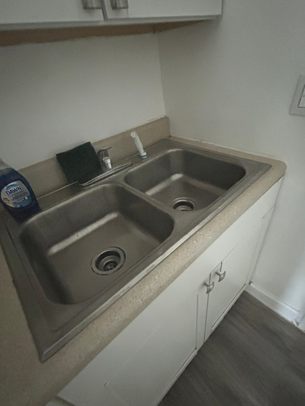 A double sink in a kitchen with a black soap dish on the counter.