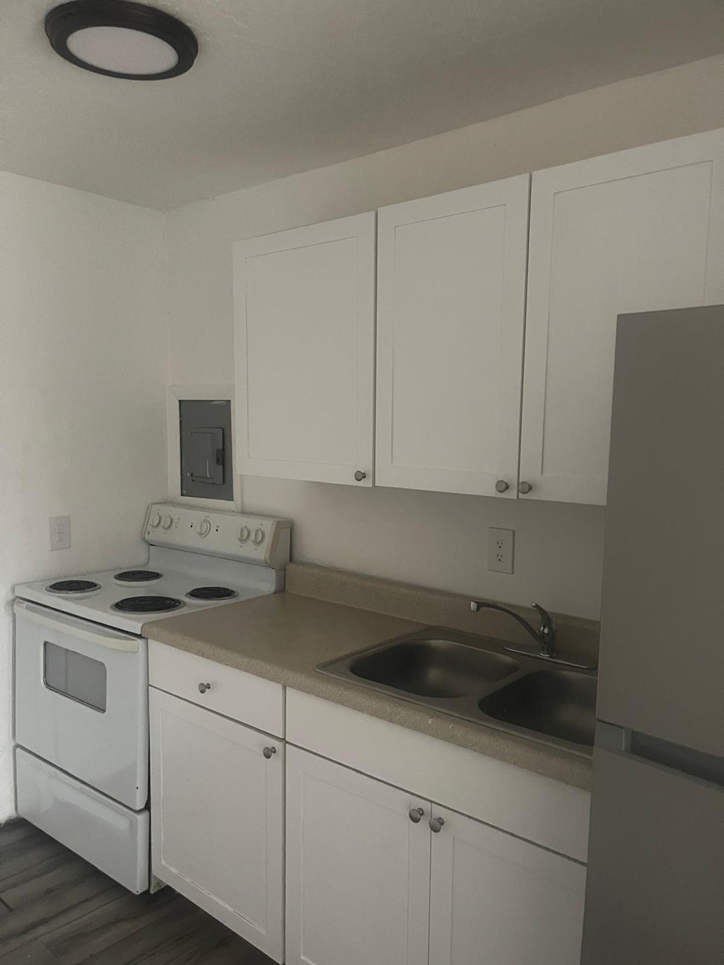 A white kitchen with a stove, sink, and cabinets.