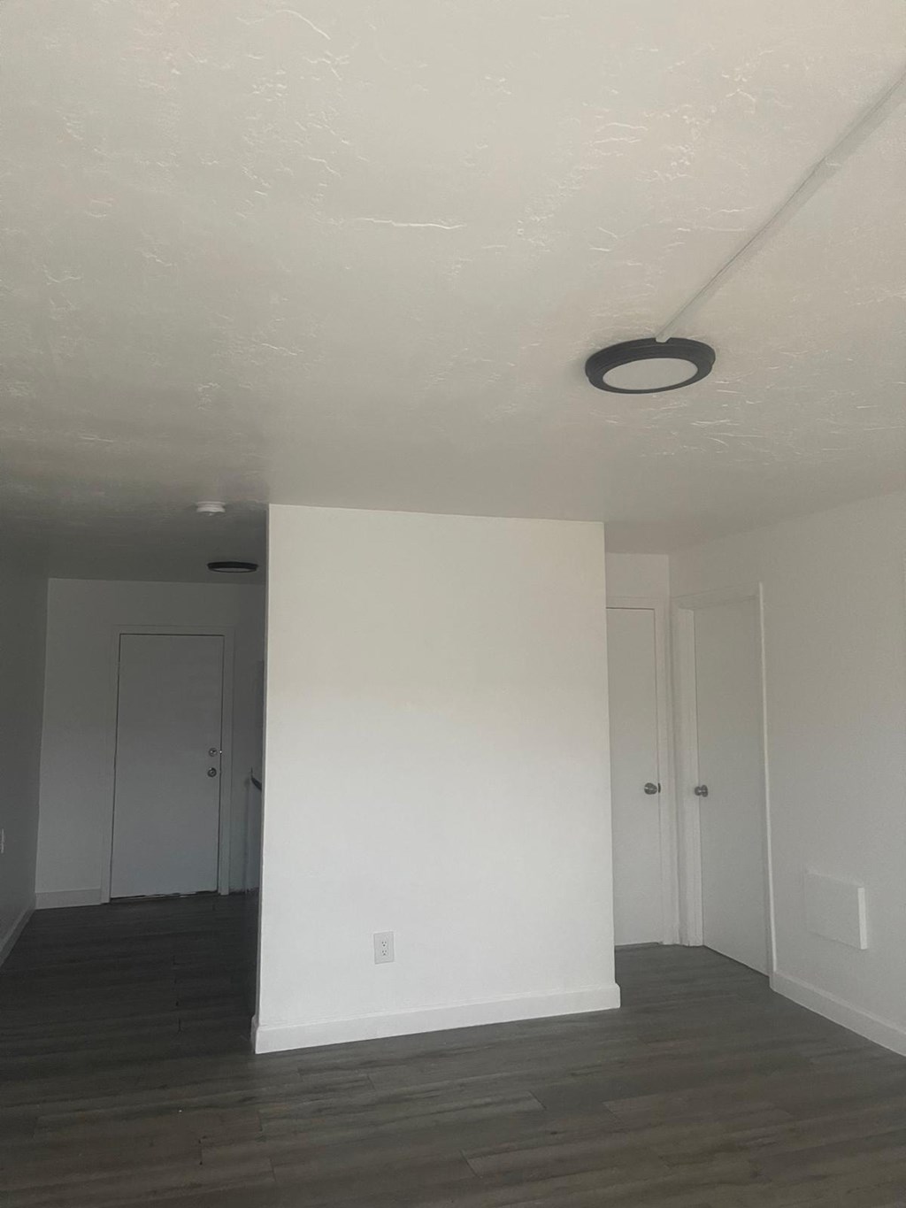 A room with white walls and a black circular light fixture on the ceiling.