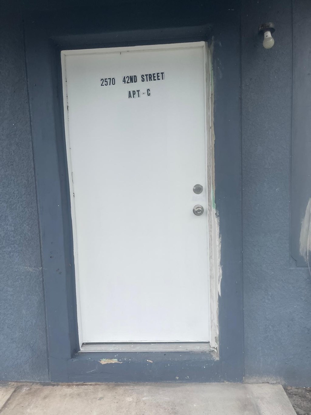 A white door with a sign above it that says 2570 42nd street APT-C.