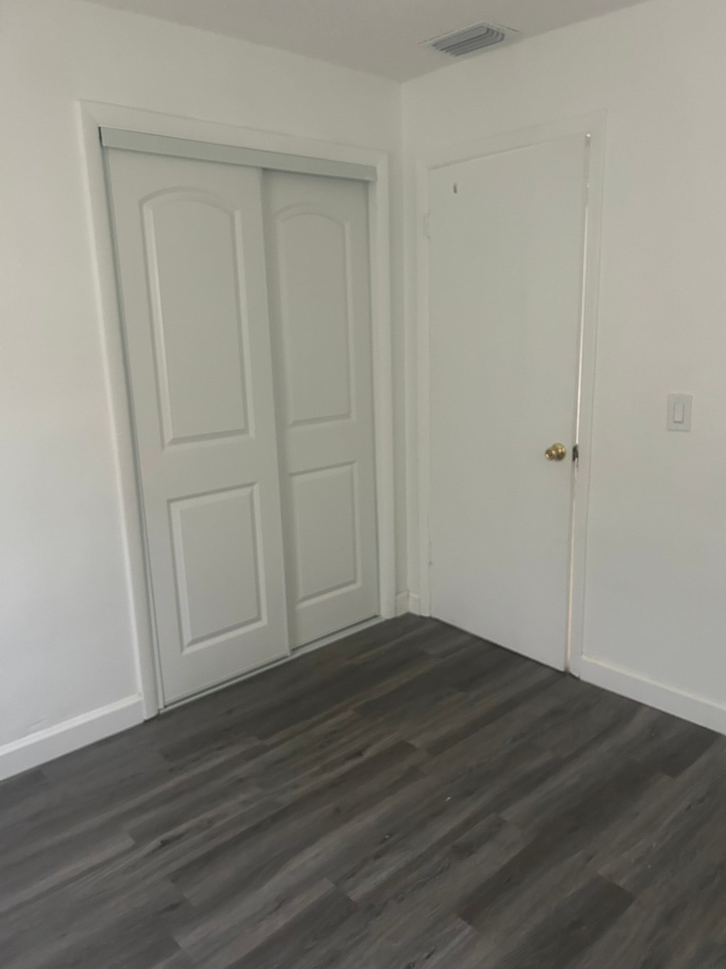 A room with a white door and a grey floor.