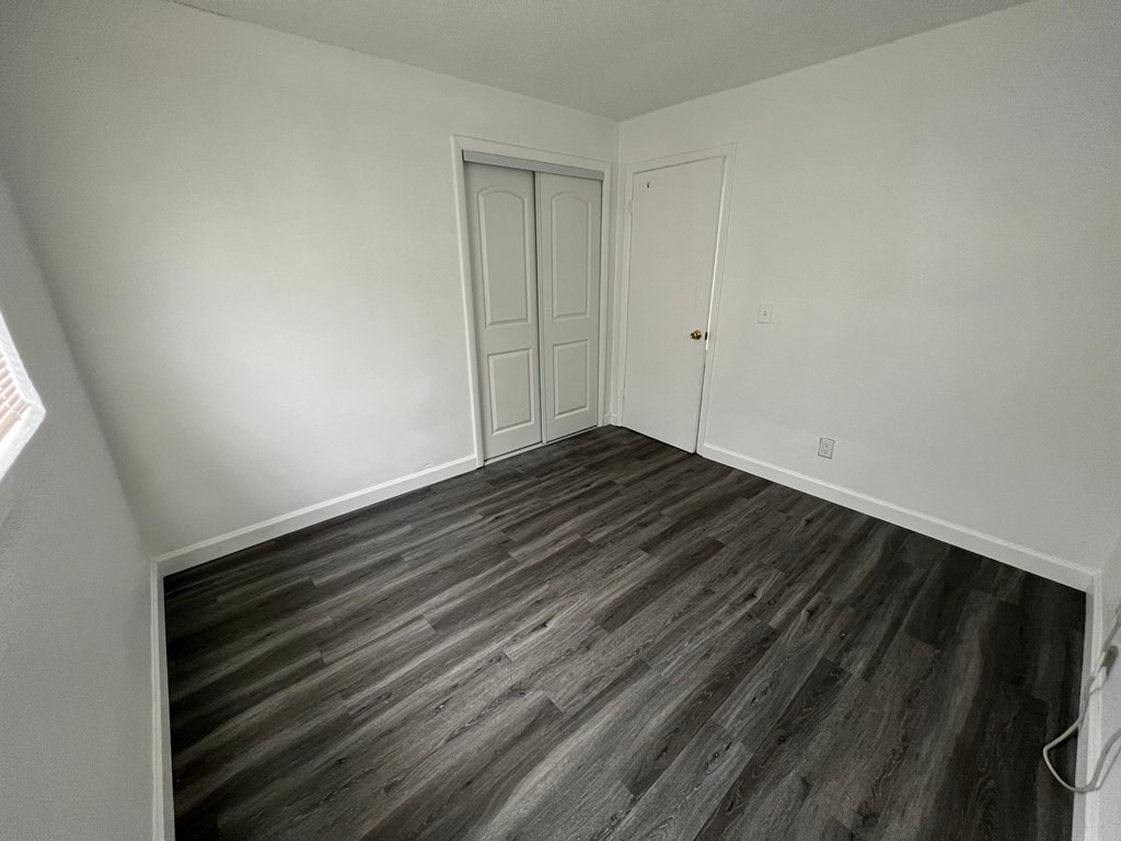 A room with a wooden floor and two doors.