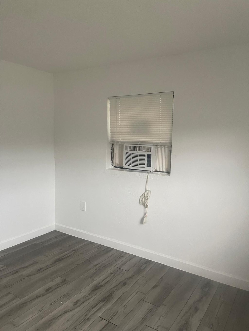 A room with a window covered by a white blind.