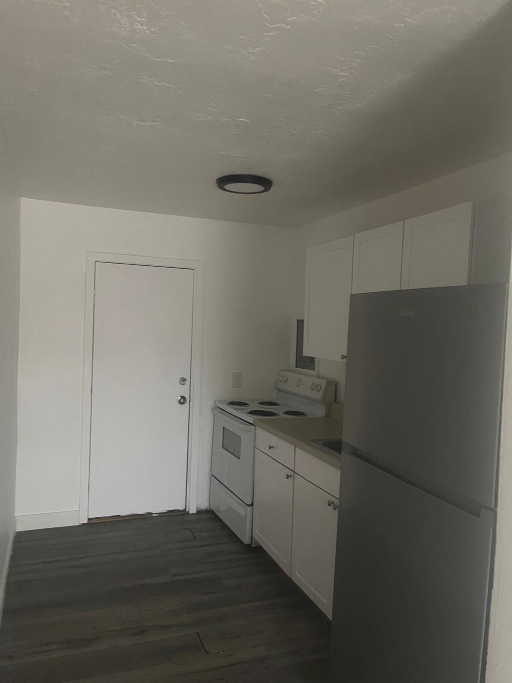 A kitchen with white cabinets and a white door.