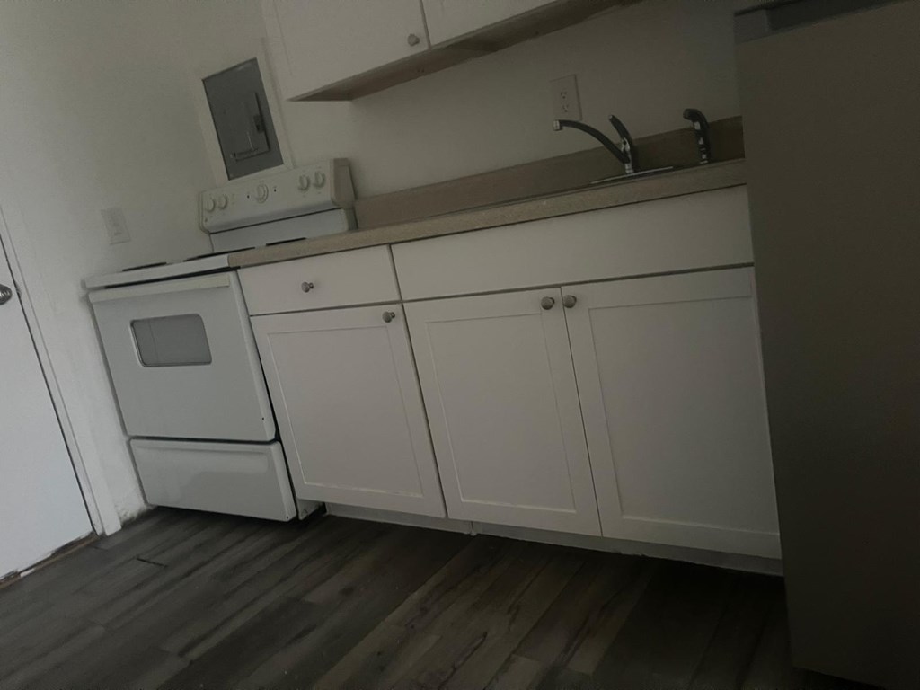 A kitchen with white cabinets and a microwave on top of the counter.