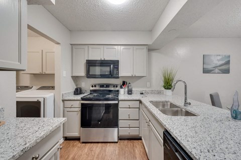 a kitchen with granite counter tops and white cabinets