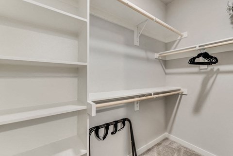 a walk in closet with white shelving and white walls and a white closet door