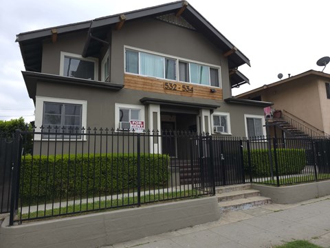 A two-story house with a black fence in front.