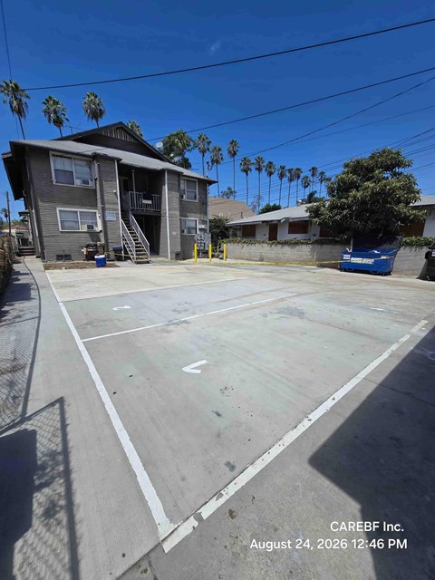 A basketball court with a building and palm trees in the background.