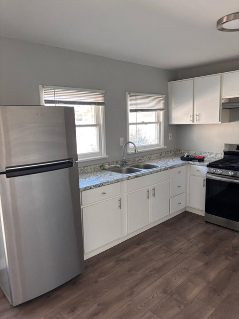 A kitchen with a stainless steel refrigerator, sink, and stove.