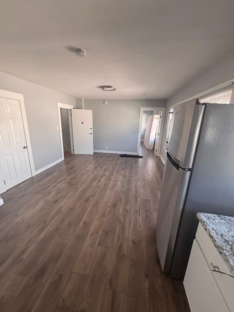 A kitchen with a refrigerator and wooden floors.